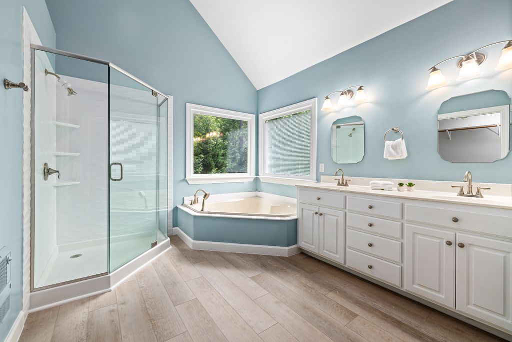 Elegant bathroom interior featuring a glass shower, bathtub, and dual sink vanity.